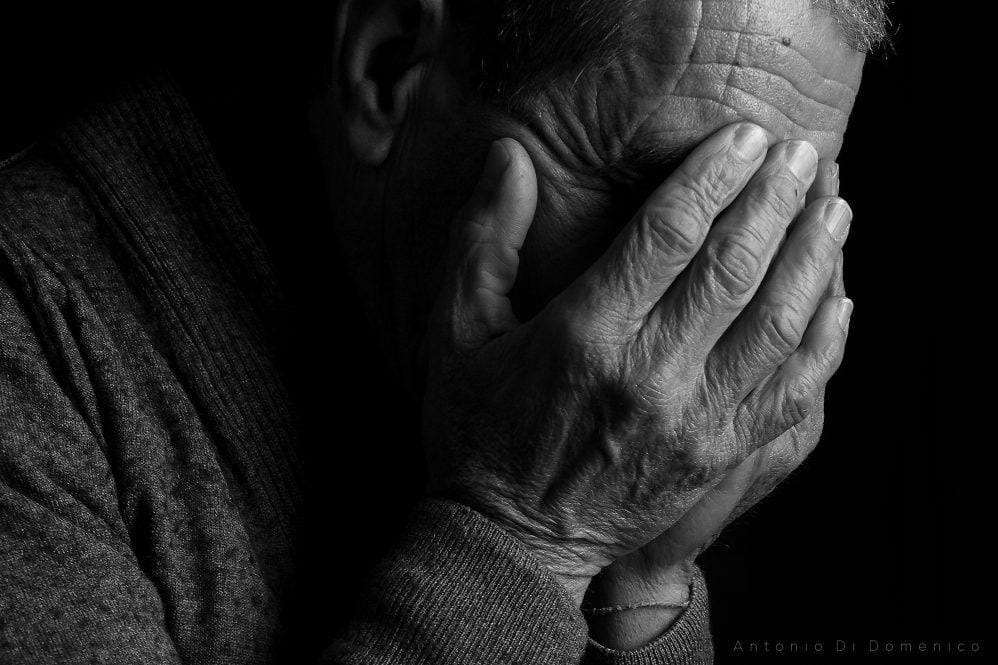 A close-up of a person holding his face
Description automatically generated